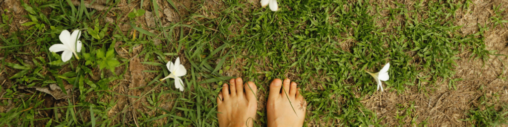 IMMAGINE DI PIEDI NUDI NELL'ERBA CON FIORI. COSA SIGNIFICA RADICAMENTO.